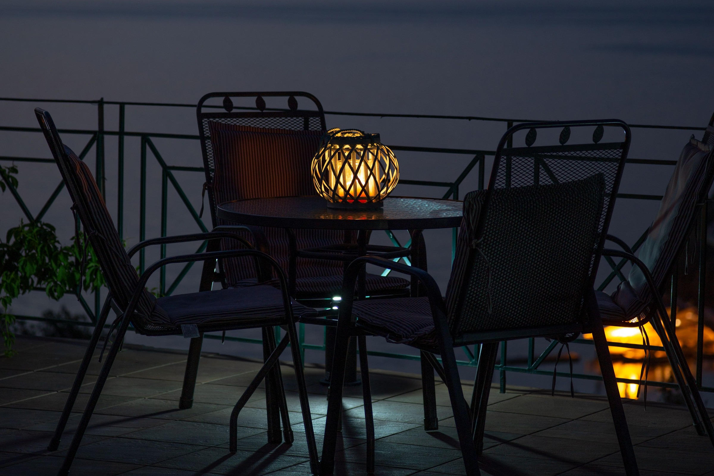 Empty chairs on a terrace above still water at dusk.